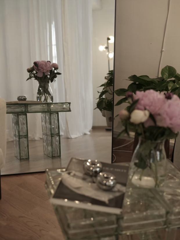 Pivoines dans un vase sur une table en briques de verre, devant le miroir